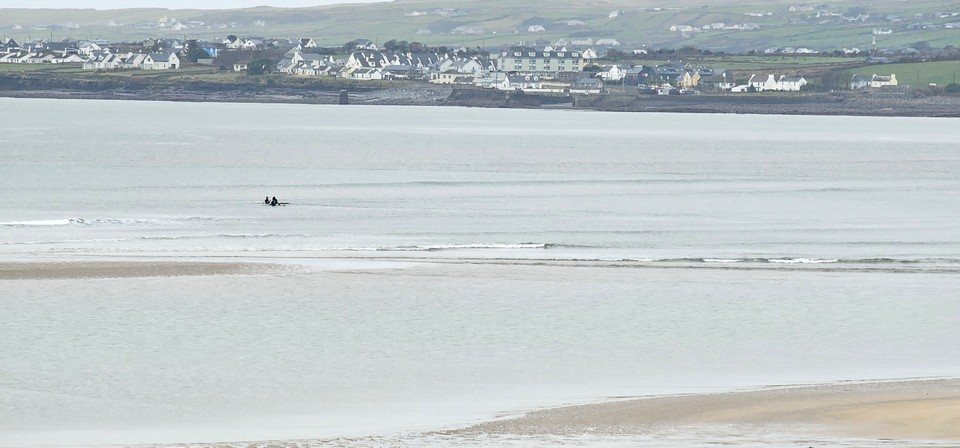 a couple of wildly optimistic surfers in the water in the middle of the beach 